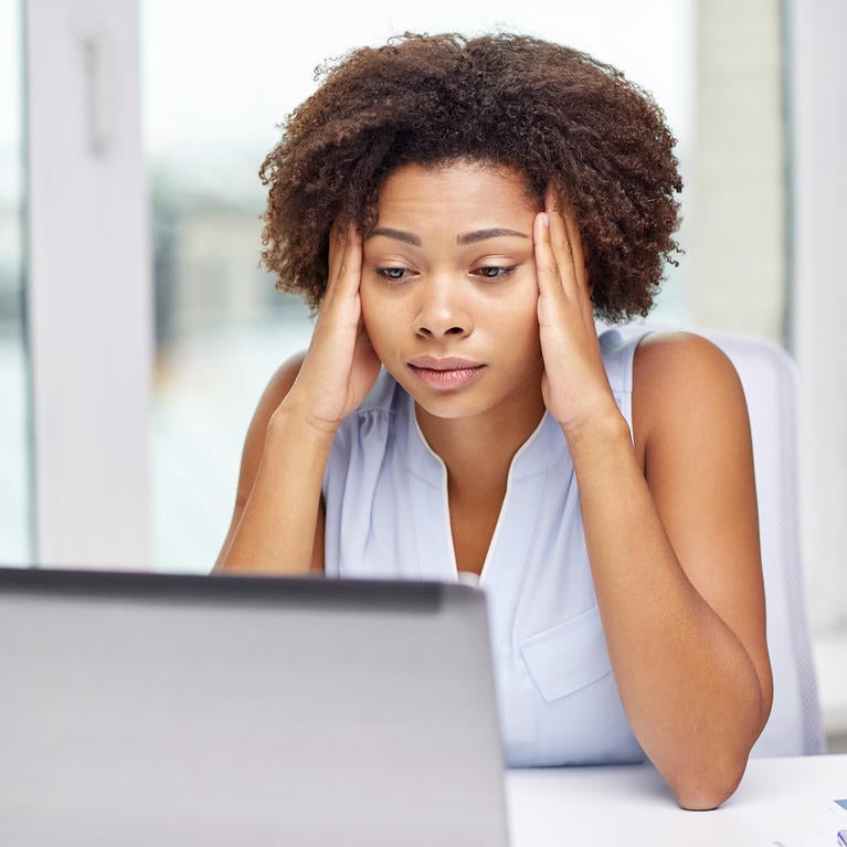 A stressed out woman sits in front of a laptop